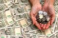 Woman’s hands with indian rupees coins. 500 rupee banknotes in background. Rupee notes & coins
